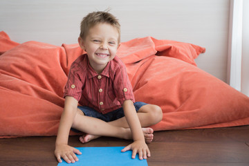 Naklejka premium The boy at home sits on the floor and makes hand-made paper.