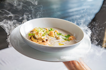 Cream mushroom soup with scallops, herbs, toast bread and dried ice mist.