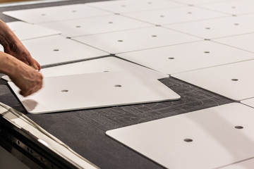 Worker, operating a cnc machine, delivering thin white boards cut into rectangular panels, ready for transport. © Edward R