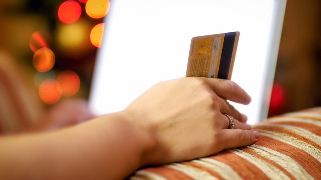 Closeup image of young woman using credit card to make purchases for Christmas