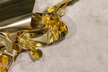 Golden crunched foil on concrete ground. 