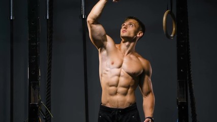 strong bodybuilder muscular athletic man with jump rope and gymnastic rings pumping up muscles workout bodybuilding background - muscular bodybuilder handsome men doing exercises in gym naked torso 4k