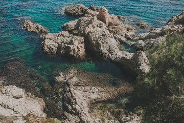 view of cliffs, a greenish-blue color bay, clear turquoise sea and andorange and green plants and trees 