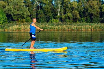 Fototapeta na wymiar Happy man paddling on a SUP board on large river