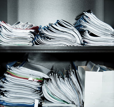 Many stitched documents, folders on the office shelf.