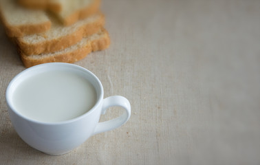 A cup of milk and pieces of white bread.