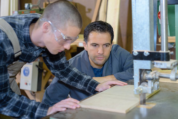 Fototapeta premium carpenter teaching apprentice how to measure wood