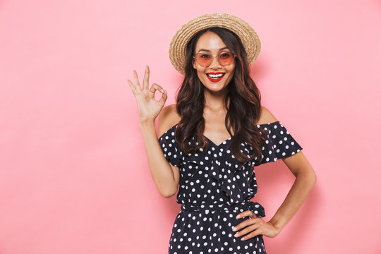 Happy brunette woman in straw hat and sunglasses posing