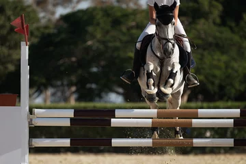 Photo sur Plexiglas Léquitation Jockey sur son cheval sautant par-dessus un obstacle, sautant par-dessus un obstacle en compétition