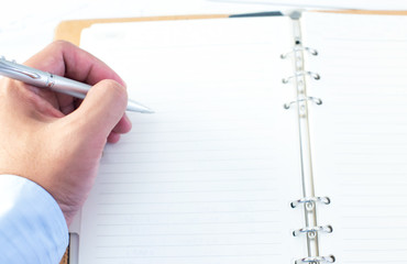 People hand holding pen closeup on open diary book closeup blur background, business,