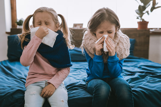 Being ill. Depressed young girls using paper tissues while being sick