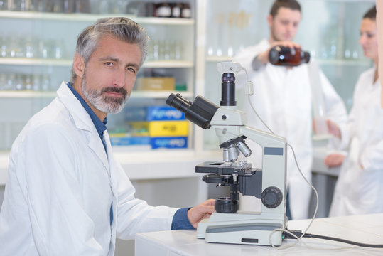 senior male scientist or tech observes sample under the microscope
