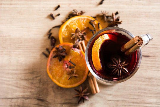 Mulled wine in glass with spice and fruit on wooden table. Top view
