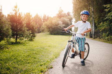 Young boy in helmet riding bicycle in park. Having fun summer day