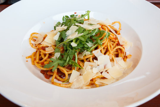 Assiette de spaghetti à la sauce tomate avec roquette et parmesan