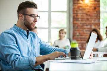 Portrait of young man sitting at his desk in the office