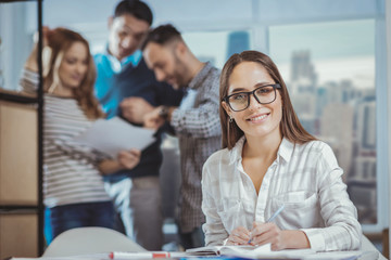 Under control. Jolly female colleague taking notes and staring at camera