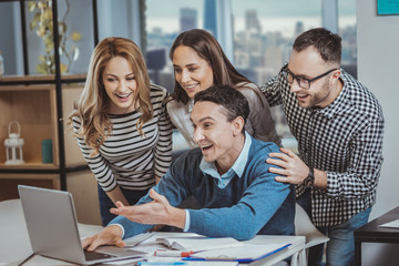 Fototapeta premium Completed presentation. Vigorous four colleagues laughing and staring at screen