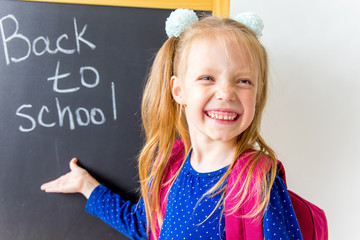 Happy cute industrious child is sitting at a desk indoors