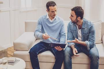 Psychological session. Serious male psychologist holding his notes while talking to his patient