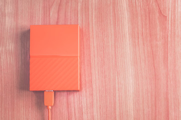 Portable orange external hard drive on the desk.