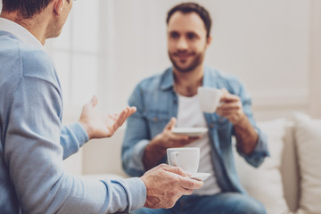 Delicious drink. Selective focus of a coffee drink being in hands of a nice male psychologist while interacting with his client
