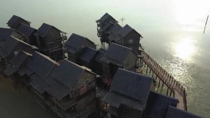 Special architecture Asia Langkawi wooden house hotel sea in water pylons. Culture is historic distinctive original. Sunset sun shine reflected in water. Malaysia. Travel exotic. Aerial Drone around