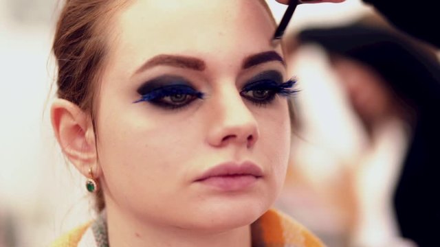 makeup artist applies makeup to model