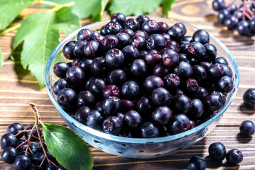 autumn harvest of black chokeberry. berries and bunches of black chokeberry close-up on a wooden background. 