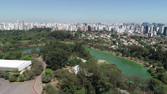 Aerial view of Ibirapuera park in Sao Paulo city, Brazil. Prevervetion area with trees and green area of Ibirapuera park. Office buildings and apartments in the background on a sunny day.