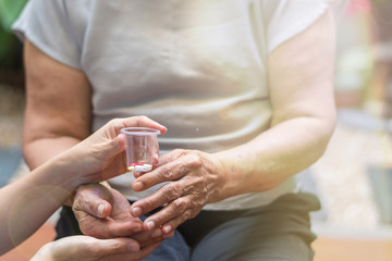Elderly female hand holding hand of young caregiver at nursing home.Geriatric doctor or geriatrician concept. Physician or nurse give medicine to happy elderly senior patient to comfort in hospital
