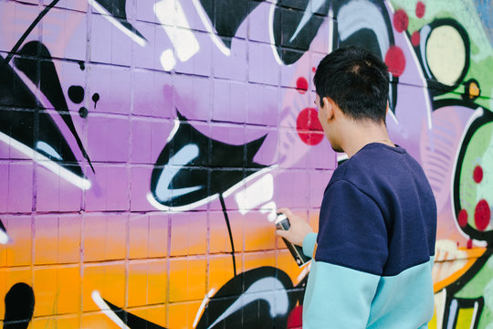 Young man graffiti artist painting on the wall