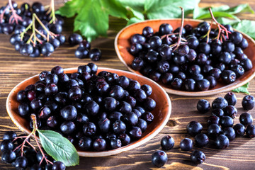 Autumn harvest of black chokeberry. berries and bunches of black chokeberry close-up on a wooden background.