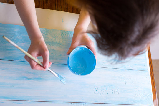 woman paints boards in blue color, handmade work