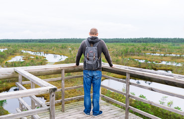 Tourist stopped on bridge with backpack to enjoy nature in summer day.