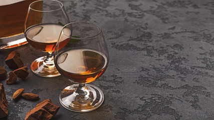 Two glasses with cognac, whiskey stones and almonds