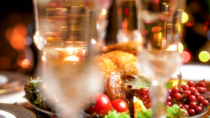 Closeup image of blurred champagne glasses against roasted chicken on Christmas dinnner