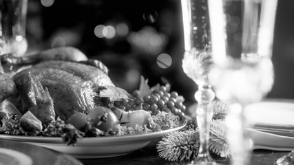 Black and white image of baked chicken and glasses with champagne on festive dining table
