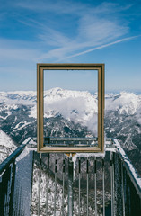 Spectacular view of clear sky and snowy mountain peaks through golden picture frame in Austrian Alps. View from Five Fingers, Obertraun