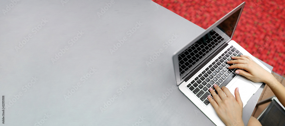 Wall mural website banner of laptop with female hands, copy space in grey color and red background. concept of 