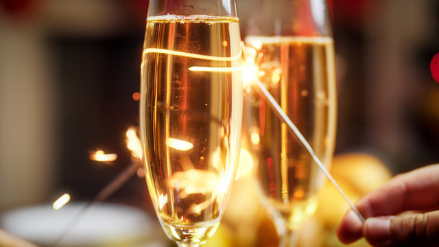 Closeup image of two sparklers behind glasses of champagne