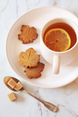 Autumn mood: lemon tea and cinnamon cookie in the form of maple leaf