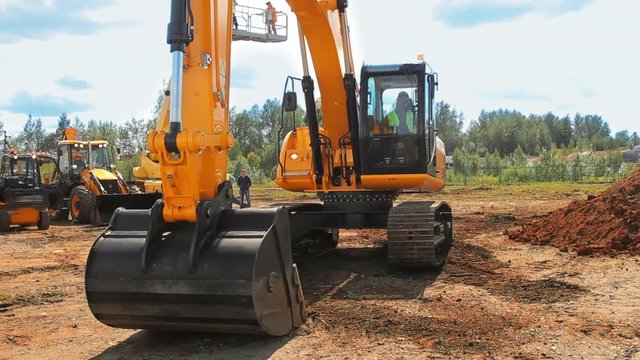 Heavy caterpillar excavator working on construction site. Orange excavator bucket work in quarry. Big powerful construction machine with excavator bucket. Earth moving equipment working