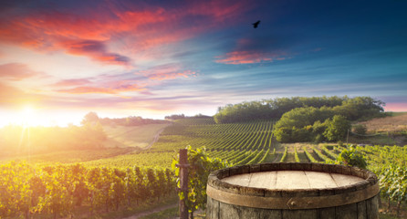Red wine bottle and wine glass on wodden barrel. Beautiful Tuscany background