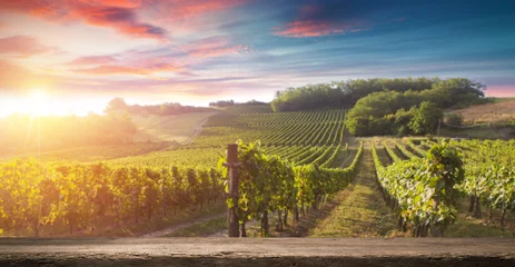 Gartenposter Weinberg Rotweinflasche und Weinglas auf Holzfass. Schöner Toskana-Hintergrund