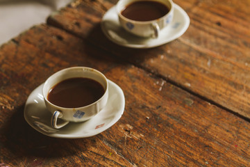 Two vintage cups of coffee in a rustic wooden table 