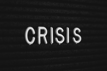 Word crisis written on the letter board. White letters on the black background
