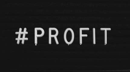 Hashtag word #profit written on the letter board. White letters on the black background