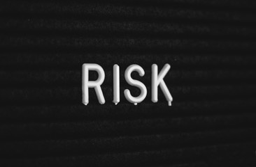 Word risk written on the letter board. White letters on the black background