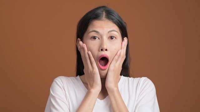 Surprise and shock woman isolated.  Portrait of asian woman in white t-shirt with shocking face expression looking at camera.